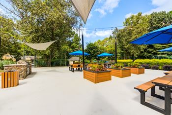 Outdoor lounge with grilling stations, table seating, and corn hole